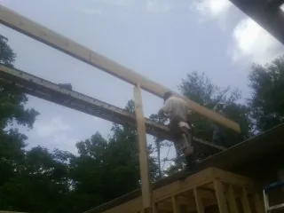 Carpenter setting a ridge beam over a new addition frame — Ice Dam Removal by Roofing Brothers in Renner