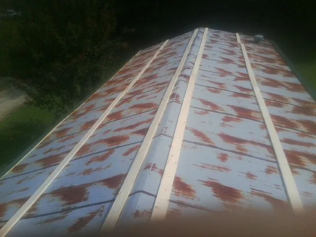 Rusted metal roof panels with new wood purlins before replacement — Storm Damage Roof Repair in Renner by Roofing Brothers
