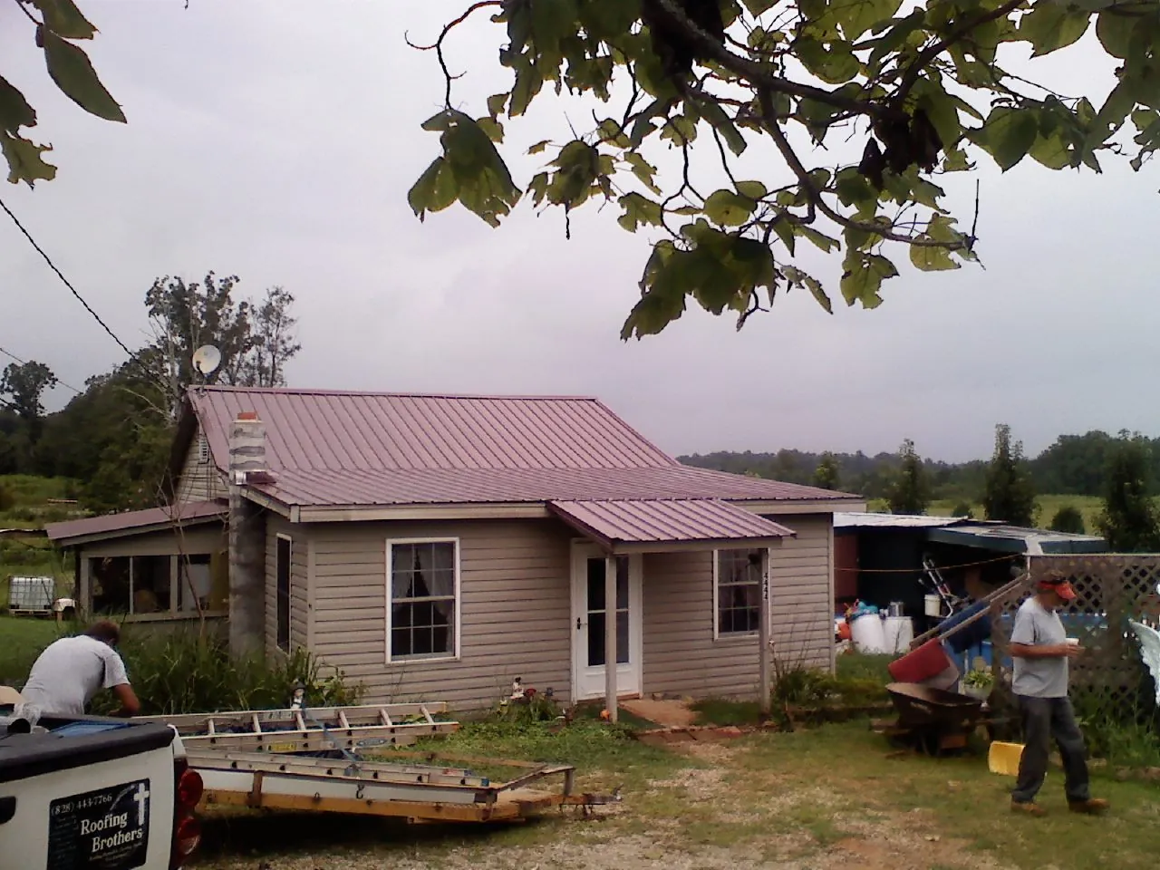 Crew finishing a mauve metal roof on a small farmhouse in Renner