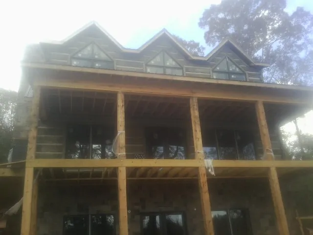 Dormers and porch framing on a large log home under construction — Roof Coating work by our crew in Renner