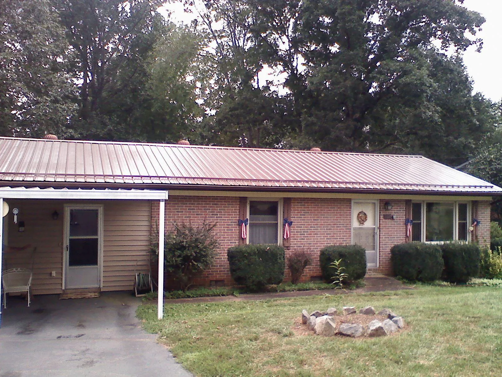 Bronze metal roof and carport on a brick ranch home — Roof Repair work by our crew in Renner