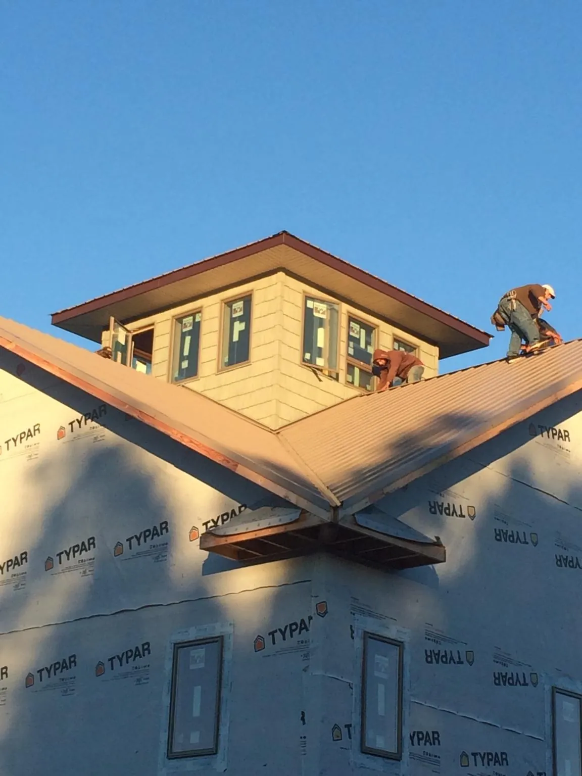 Roofers working around a rooftop cupola on a new metal roof at sunset — Roof Waterproofing in Renner by Roofing Brothers